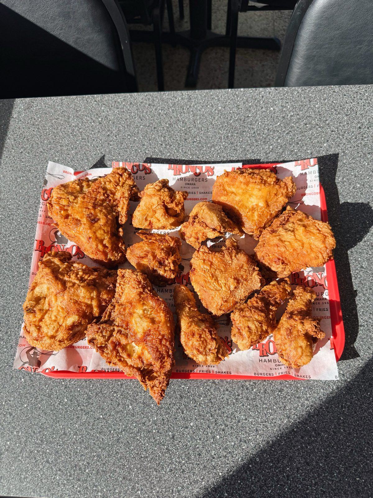 A tray of Bronco's golden fried chicken on a red-checked paper liner