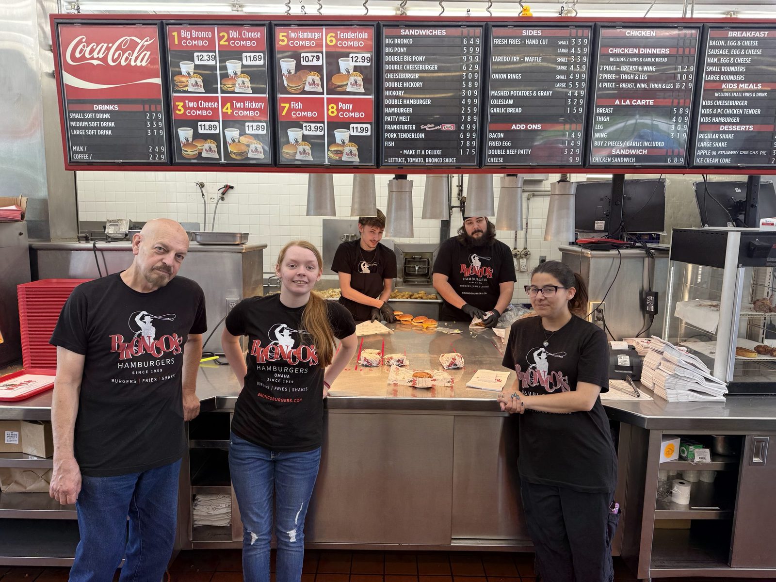 The Bronco's crew in black Bronco's shirts at the front counter under the menu boards